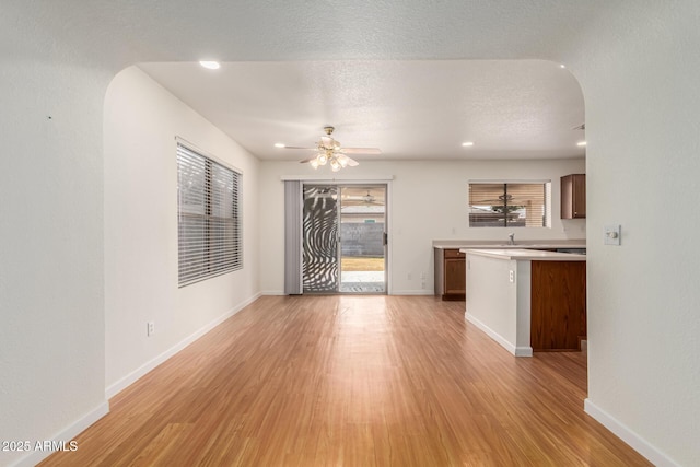 interior space featuring ceiling fan, sink, light hardwood / wood-style flooring, and a textured ceiling