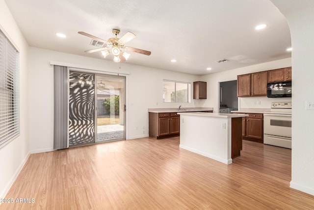 kitchen with sink, a kitchen island, electric stove, ceiling fan, and light hardwood / wood-style floors