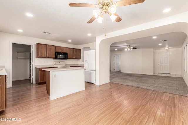 kitchen featuring white appliances, a center island, ceiling fan, and light wood-type flooring