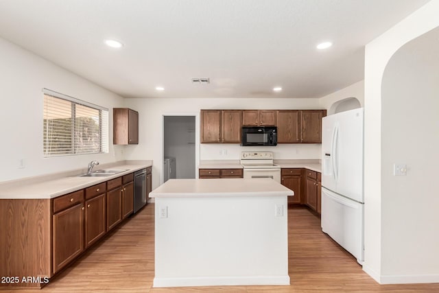 kitchen featuring independent washer and dryer, sink, a center island, white appliances, and light hardwood / wood-style floors