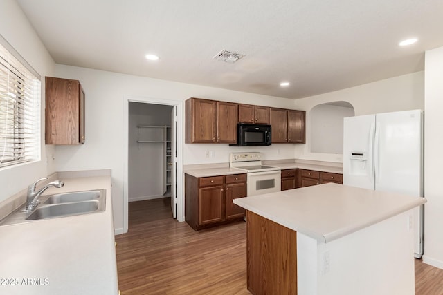 kitchen featuring wood-type flooring, a center island, sink, and white appliances