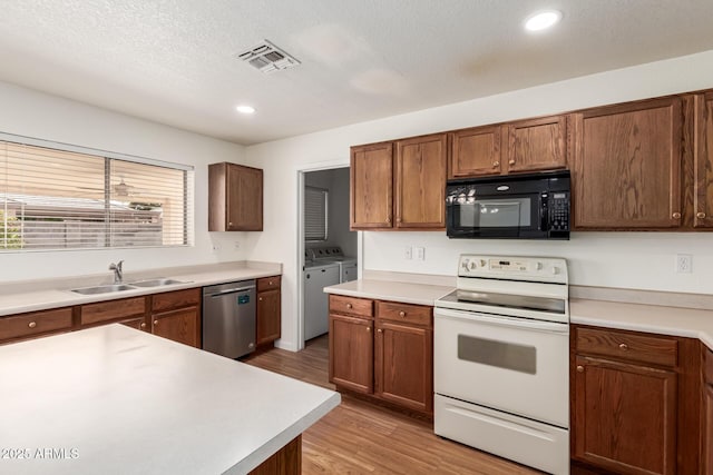 kitchen featuring sink, white electric range oven, separate washer and dryer, stainless steel dishwasher, and light wood-type flooring