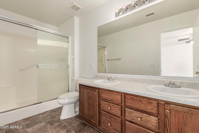 bathroom featuring vanity, ceiling fan, a shower with door, and toilet