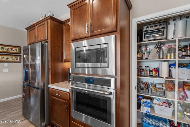 kitchen with light stone counters, light hardwood / wood-style flooring, and appliances with stainless steel finishes