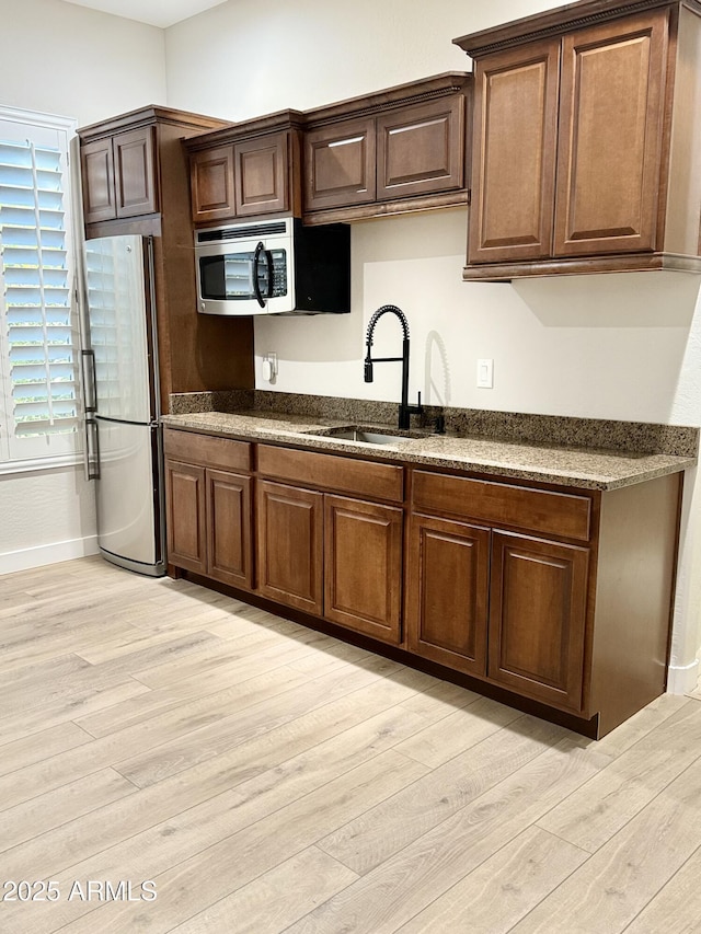 kitchen with sink, stainless steel appliances, and light hardwood / wood-style floors