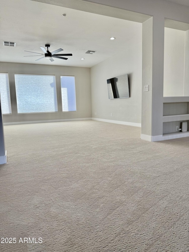 unfurnished room featuring ceiling fan, built in shelves, and light carpet