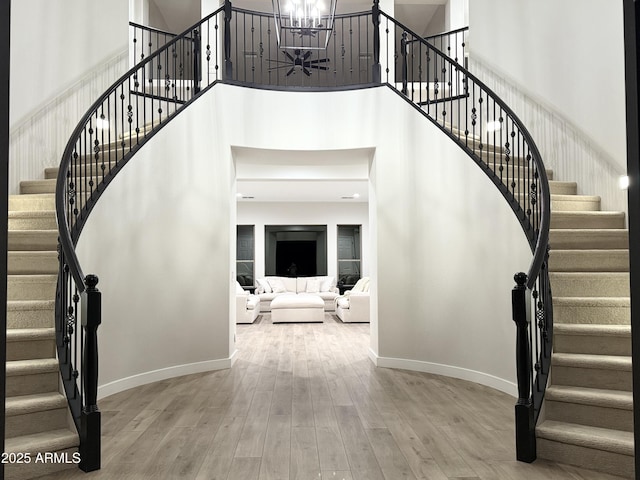 stairway featuring hardwood / wood-style flooring, a chandelier, and a towering ceiling