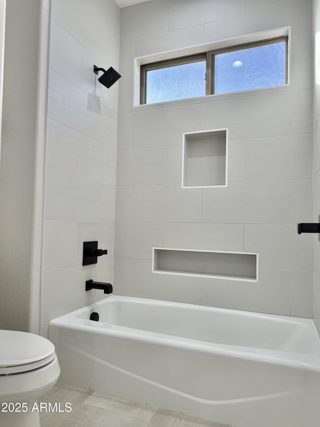 bathroom featuring toilet, tile patterned flooring, and tiled shower / bath