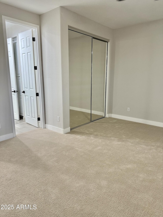 unfurnished bedroom with light colored carpet and a closet