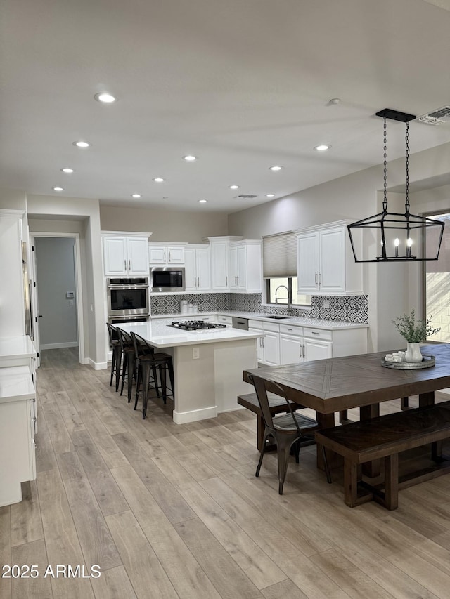 kitchen featuring stainless steel oven, a center island, built in microwave, gas stovetop, and hanging light fixtures