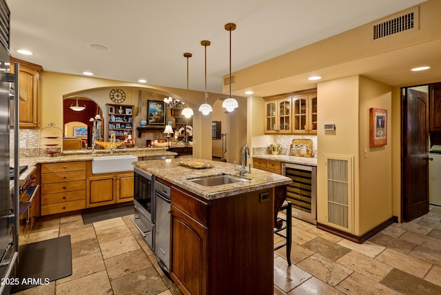 kitchen featuring sink, a center island with sink, kitchen peninsula, a kitchen bar, and beverage cooler