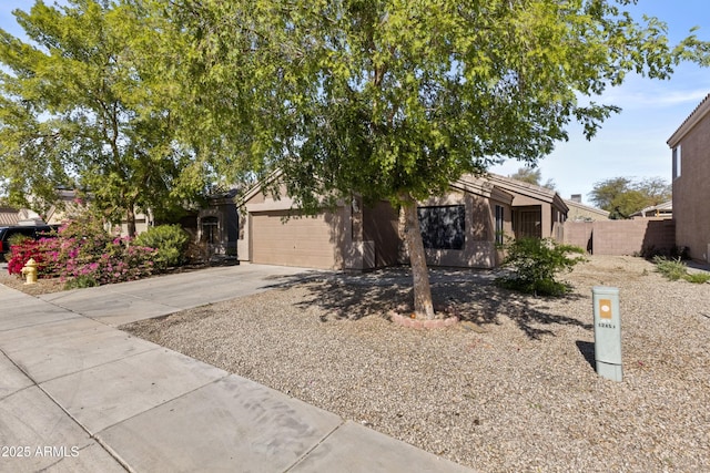 obstructed view of property featuring a garage, driveway, fence, and stucco siding