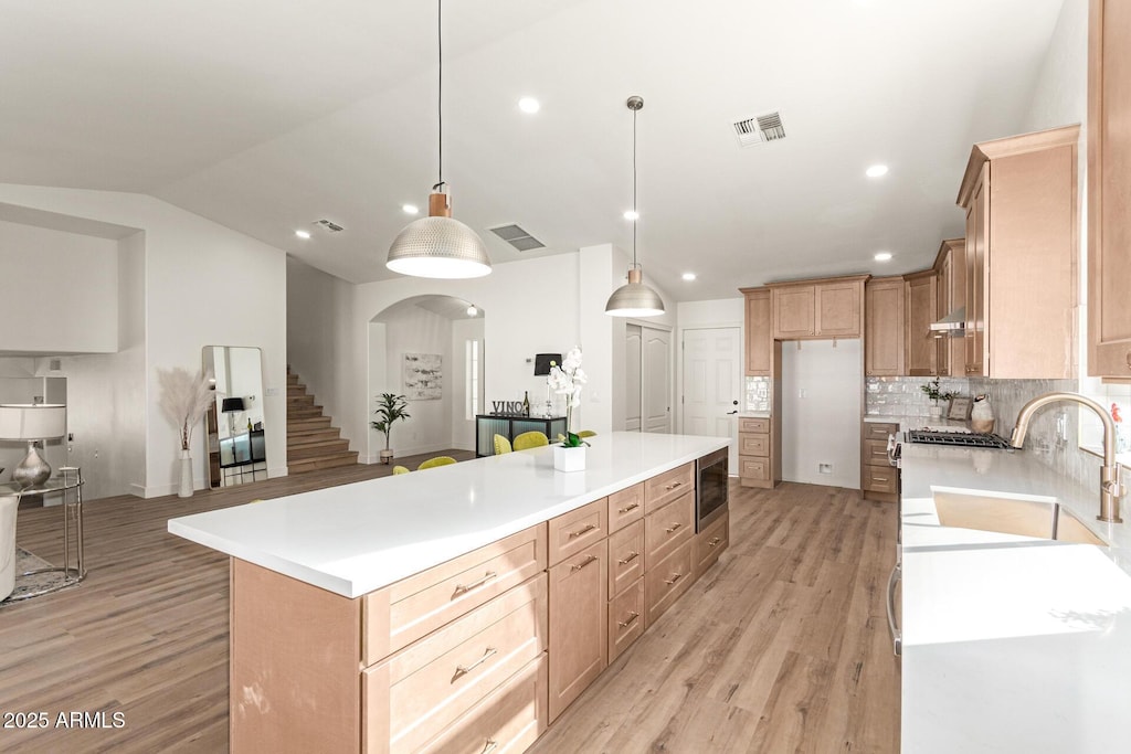 kitchen featuring decorative light fixtures, sink, a kitchen island, and light hardwood / wood-style flooring