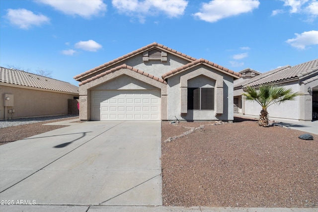 mediterranean / spanish house featuring driveway, a tiled roof, an attached garage, and stucco siding