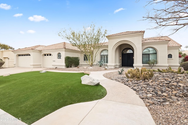 mediterranean / spanish home featuring a garage and a front yard