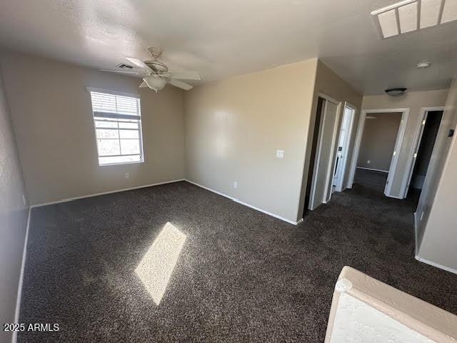 unfurnished room featuring dark carpet, visible vents, and baseboards