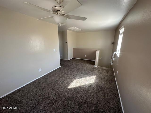 spare room with dark colored carpet, a ceiling fan, and baseboards