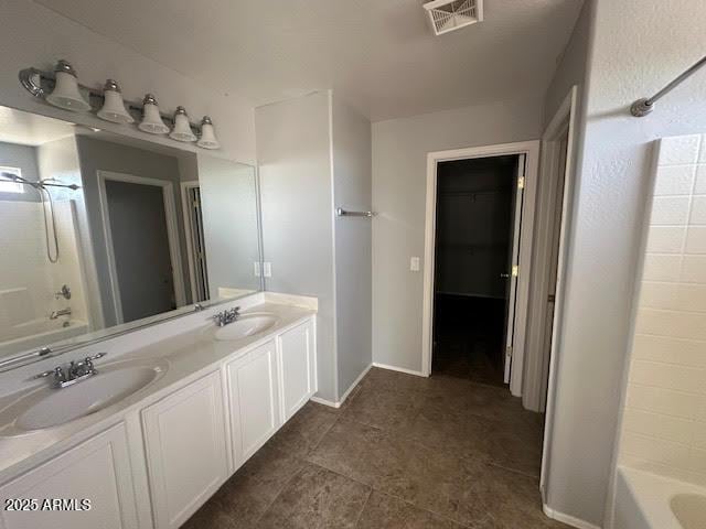 bathroom with double vanity, shower / bath combination, visible vents, and a sink