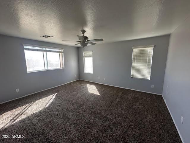 unfurnished room with a textured ceiling, carpet, visible vents, and a ceiling fan