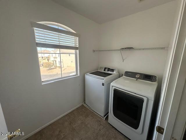 clothes washing area with laundry area, baseboards, and washer and dryer