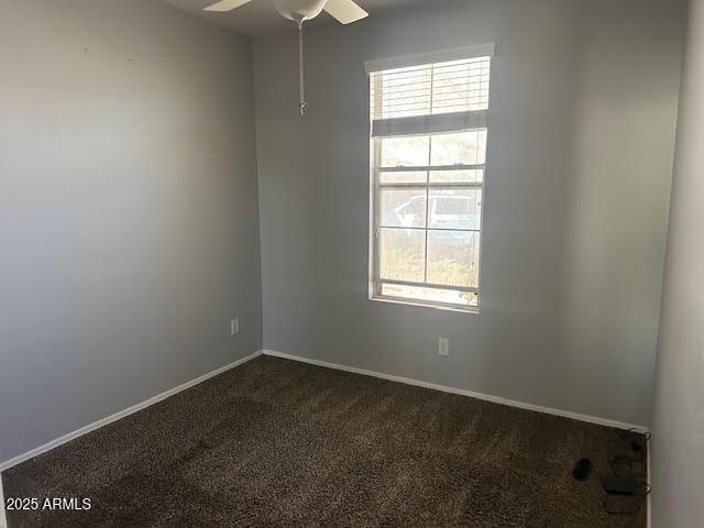 spare room with dark colored carpet, ceiling fan, and baseboards