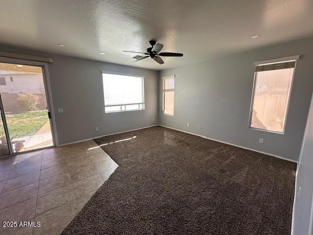 empty room with a ceiling fan, a textured ceiling, baseboards, and light tile patterned floors