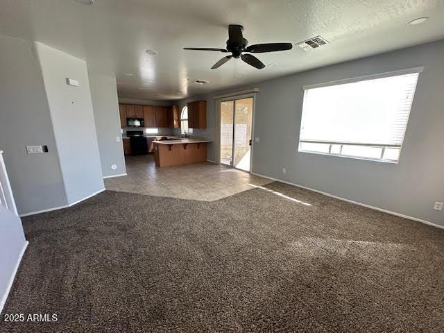 kitchen featuring carpet floors, brown cabinetry, open floor plan, black microwave, and range