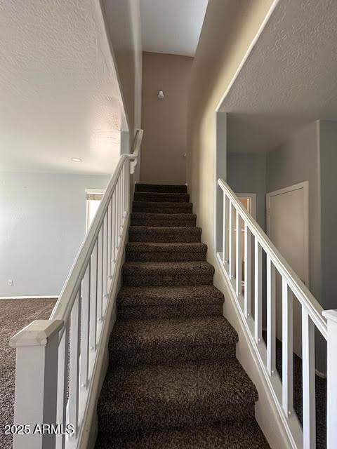 staircase with carpet flooring and a textured ceiling