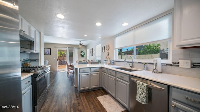 kitchen featuring dark hardwood / wood-style flooring, backsplash, stainless steel appliances, sink, and gray cabinets