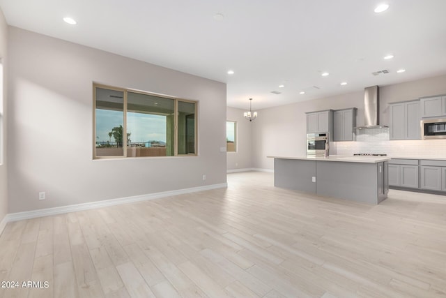 kitchen featuring gray cabinets, an island with sink, sink, and light hardwood / wood-style floors