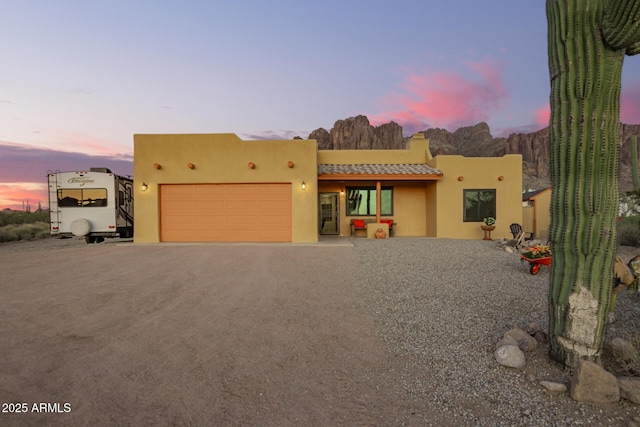 southwest-style home featuring driveway, a garage, stucco siding, and a tiled roof