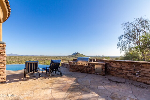 view of patio / terrace with area for grilling, an outdoor kitchen, and a mountain view