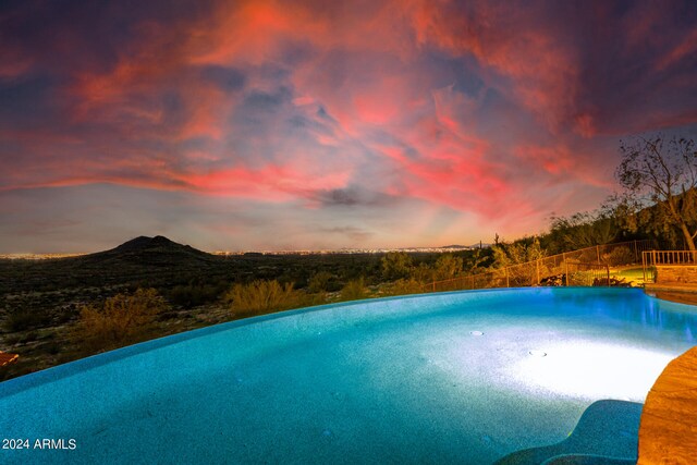 pool at dusk featuring a mountain view