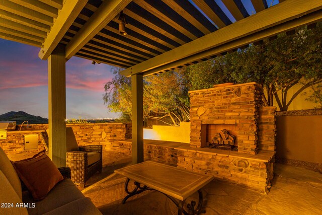 patio terrace at dusk featuring an outdoor stone fireplace