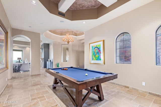 rec room with light tile floors, a notable chandelier, billiards, a high ceiling, and a raised ceiling