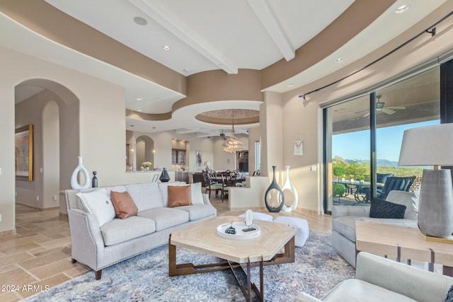 living room featuring beam ceiling, light tile floors, and ceiling fan with notable chandelier