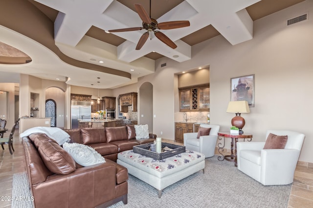 tiled living room featuring coffered ceiling, ceiling fan, and sink