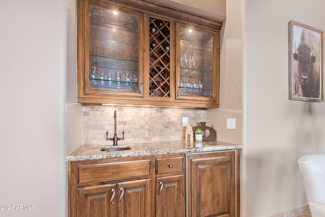 bar with sink, tasteful backsplash, and light stone countertops