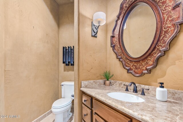 bathroom featuring toilet, vanity with extensive cabinet space, and tile flooring