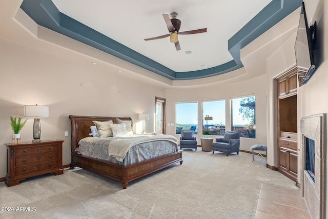 bedroom with light carpet, a tray ceiling, and ceiling fan