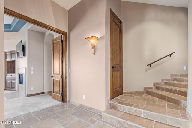 staircase with light tile flooring and high vaulted ceiling