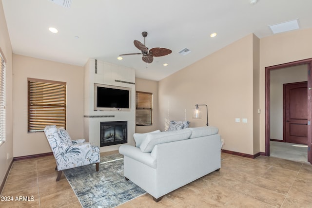 tiled living room with a fireplace, ceiling fan, and a skylight