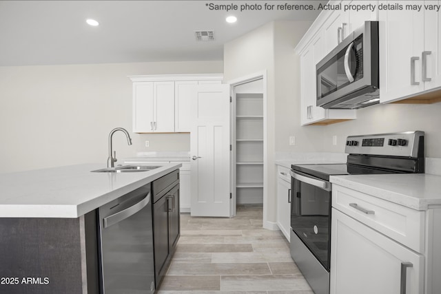 kitchen with sink, light hardwood / wood-style floors, white cabinets, and appliances with stainless steel finishes