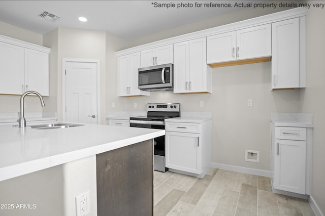 kitchen featuring appliances with stainless steel finishes, sink, white cabinets, and light hardwood / wood-style floors