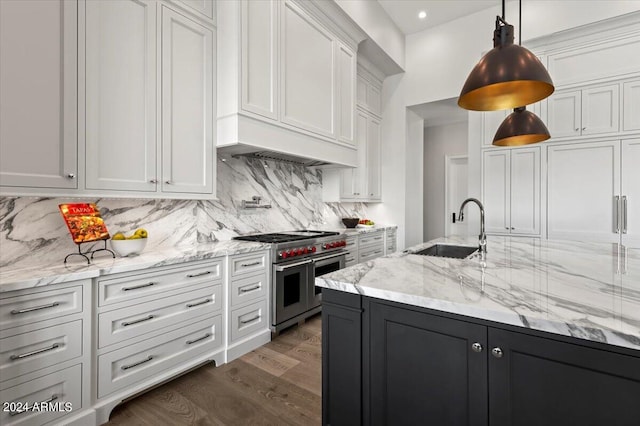 kitchen with double oven range, decorative light fixtures, sink, and white cabinets