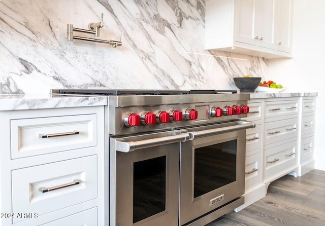 kitchen featuring dark hardwood / wood-style floors, light stone countertops, range with two ovens, and white cabinets