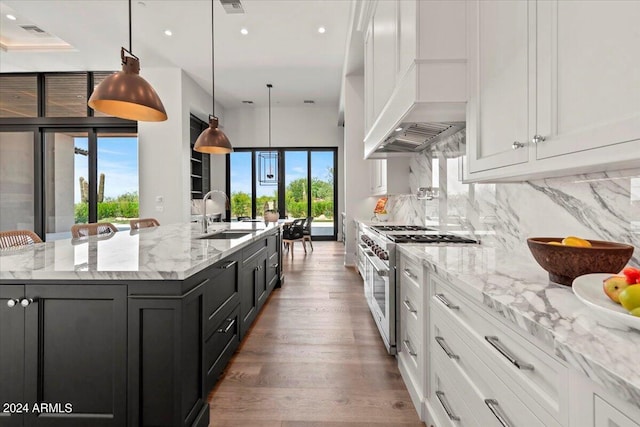 kitchen with white cabinetry, sink, stainless steel range, and a spacious island