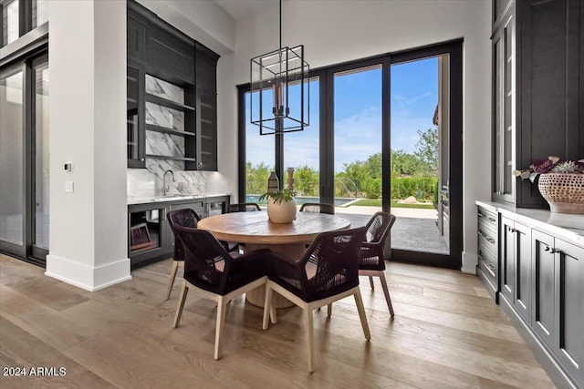 dining room with sink, a chandelier, and light hardwood / wood-style flooring