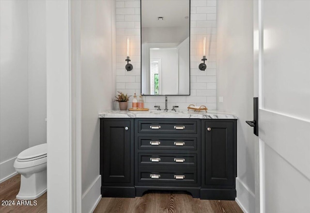 bathroom featuring wood-type flooring, vanity, decorative backsplash, and toilet