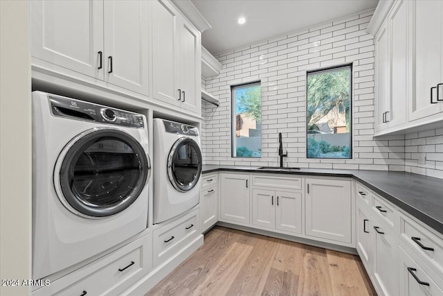 laundry area featuring cabinets, washing machine and dryer, sink, and light hardwood / wood-style flooring